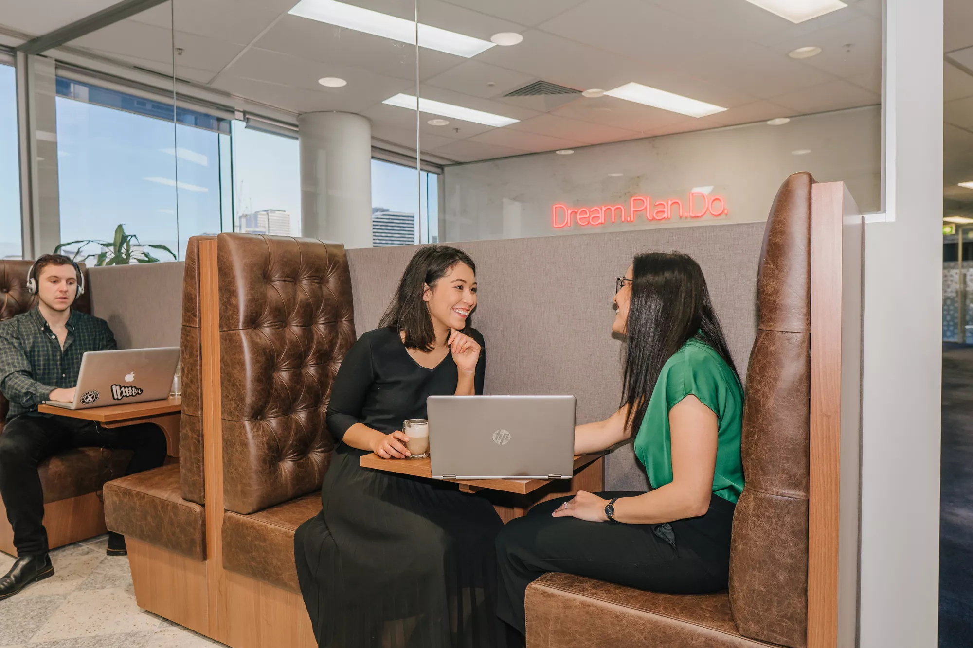 Clients working and conversing in a modern coworking space and booths in Servcorp Southbank, Melbourne