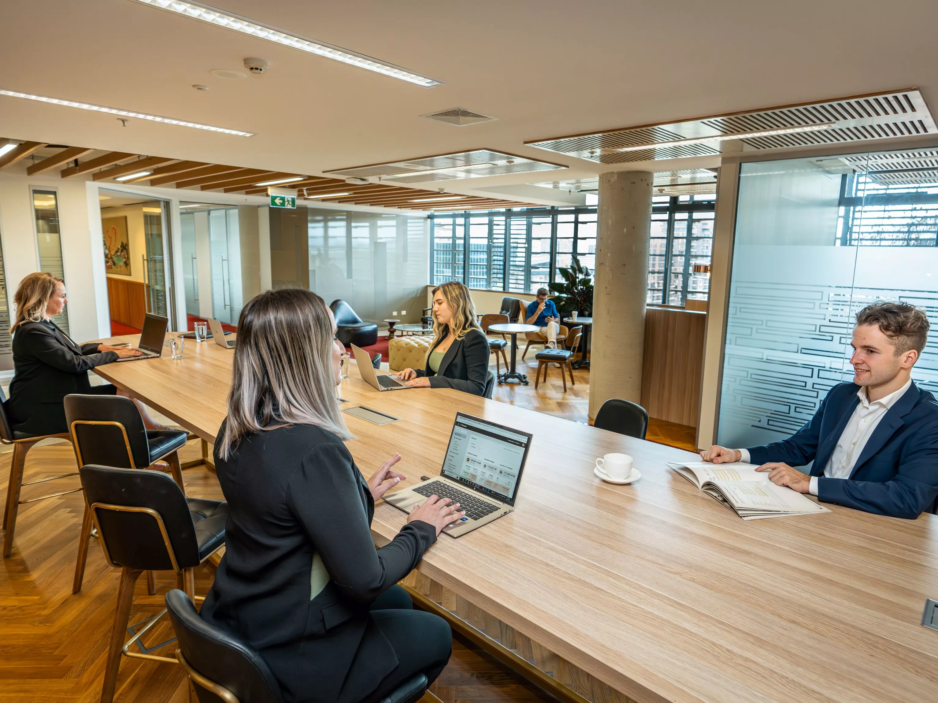 Clients working in a modern coworking space on a long table and hot desk, in Servcorp Nishi Building, Canberra