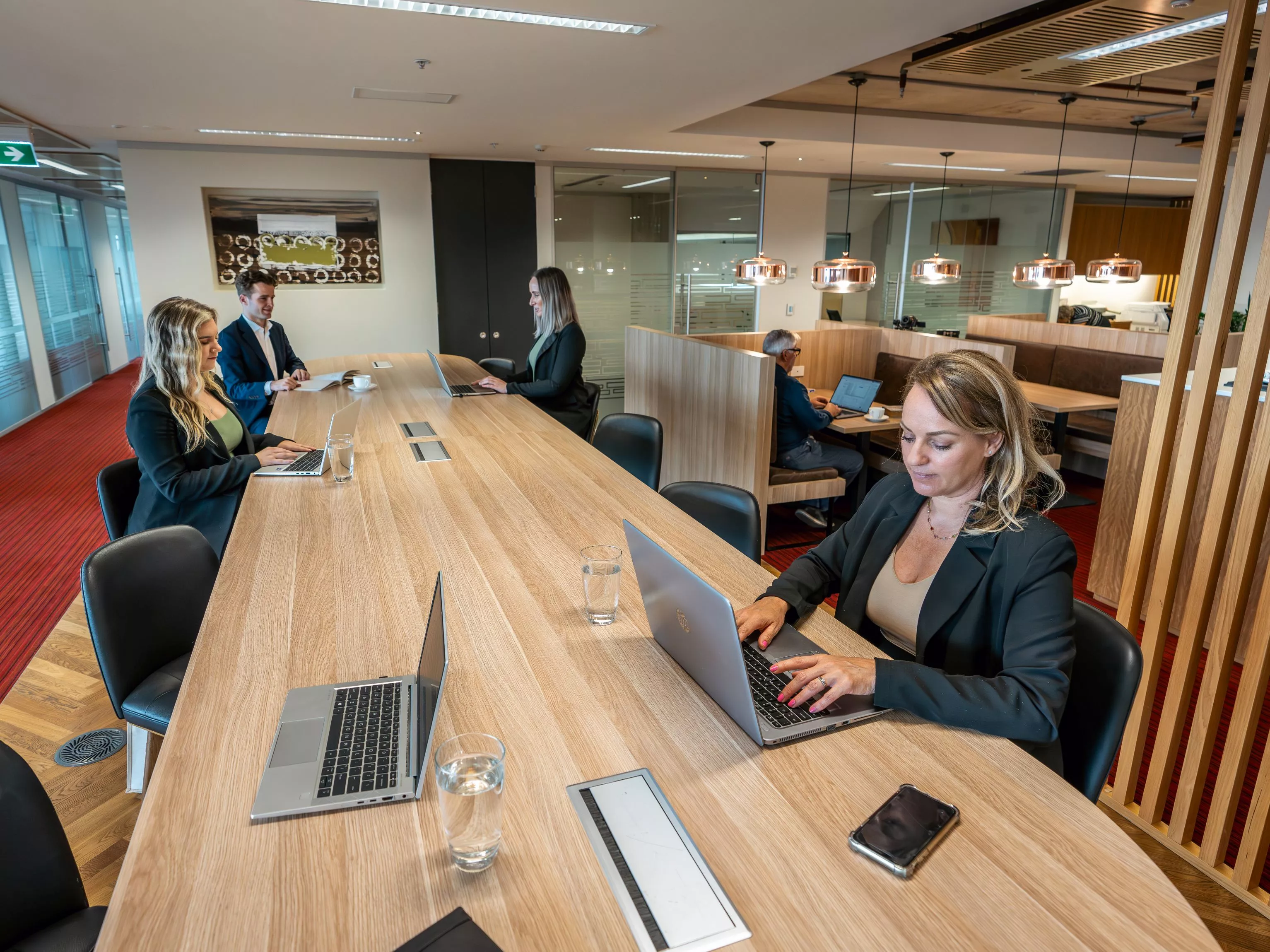 Clients working in a modern coworking space on a long table, in Servcorp Nishi Building, Canberra