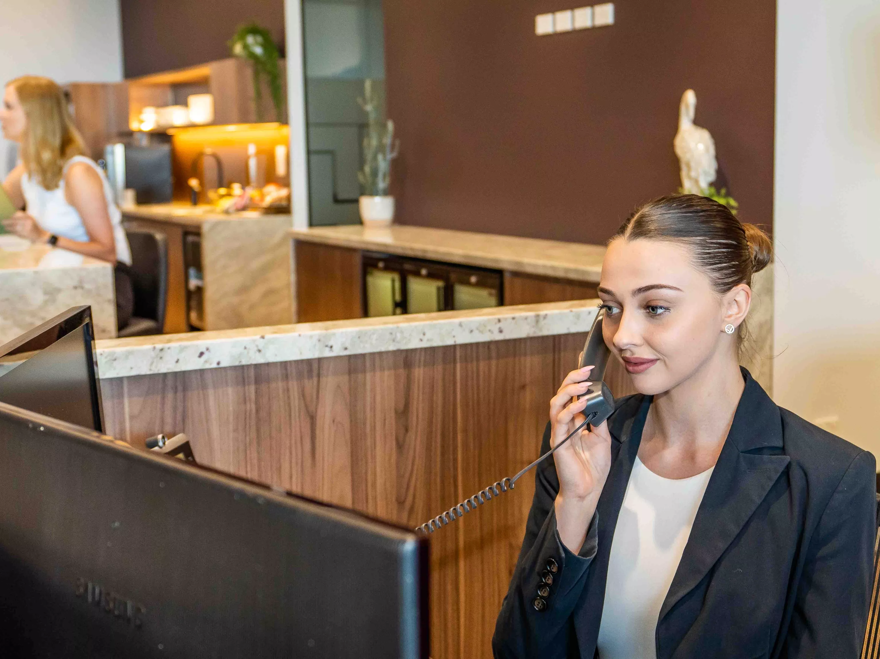 A dedicated receptionist helping a client on the phone in the modern co-working space of in Servcorp 100 Mount Street