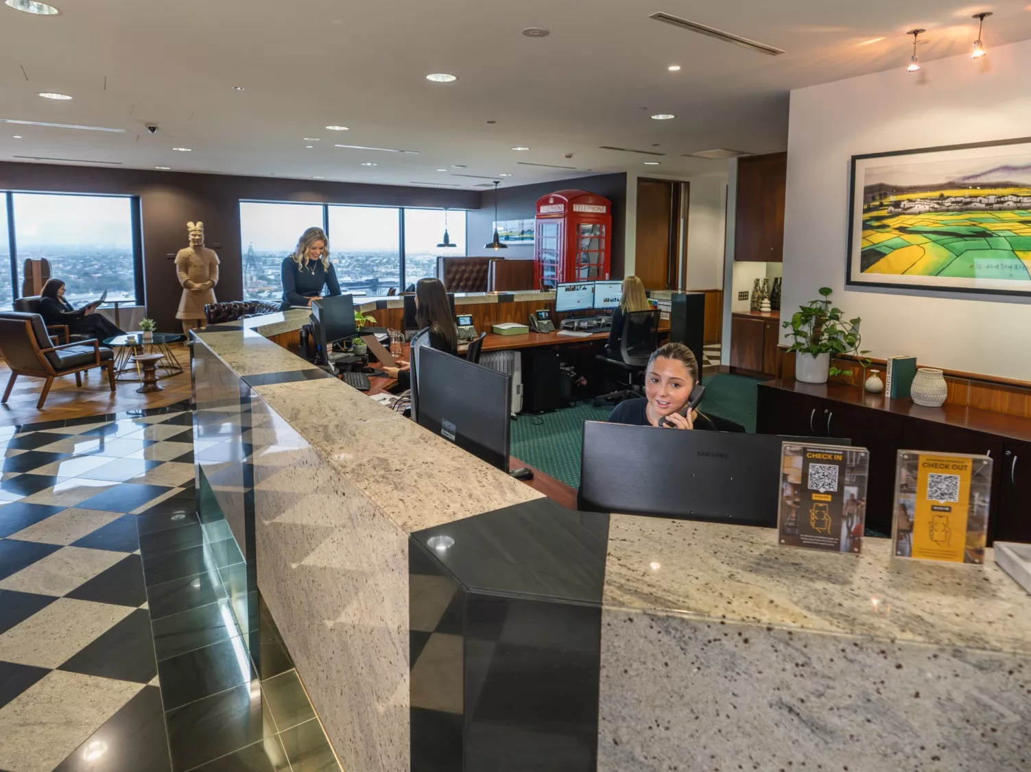 A client talking to the receptionist and another on the phone in a modern coworking space in Servcorp 44 Market Street