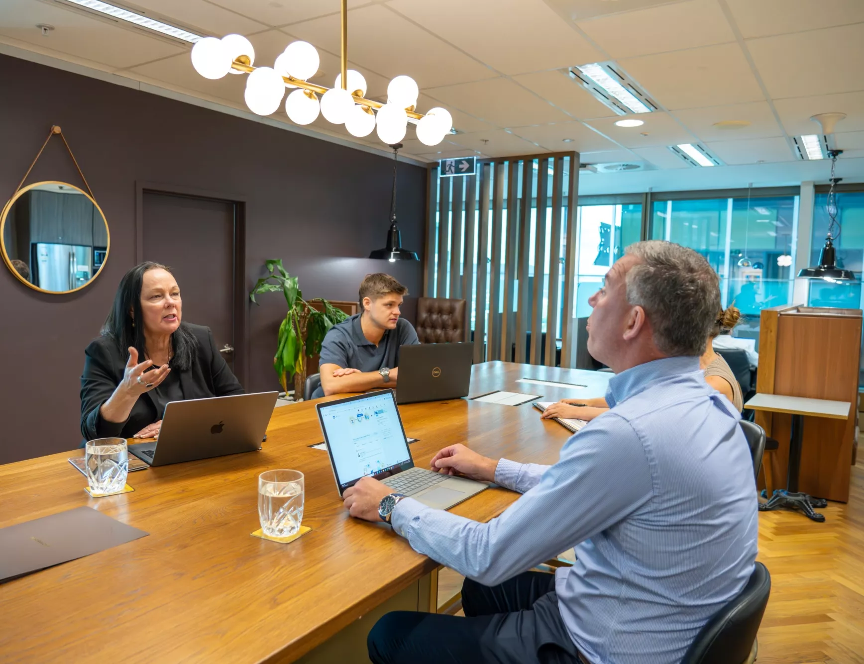 Clients working in a coworking space on a large table in a modern space in Servcorp Santos Place, Brisbane